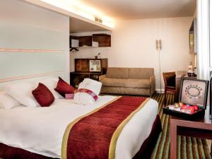 a hotel room with a large bed and a couch at Mercure Paris Ivry Quai De Seine in Ivry-sur-Seine