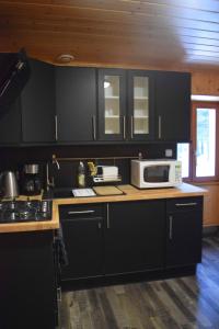 a kitchen with black cabinets and a microwave on a counter at Les gîtes de la Serva in Belmont