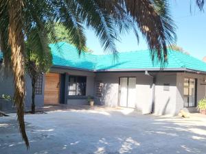 Hephzibah Guesthouse في ولكوم: منزل بسقف أخضر وأشجار نخيل