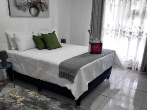 een slaapkamer met een groot bed met groene kussens bij Hephzibah Guesthouse in Welkom