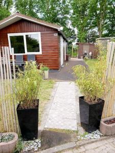 une clôture avec deux plantes en pot devant une maison dans l'établissement Tiny house Schoorl Bergen NH, à Warmenhuizen