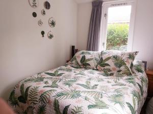 a bedroom with a bed with a floral comforter and a window at Tiny house Schoorl Bergen NH in Warmenhuizen