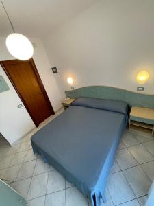 a bedroom with a blue bed and two tables at Albergo Désirée 2 in Alba Adriatica