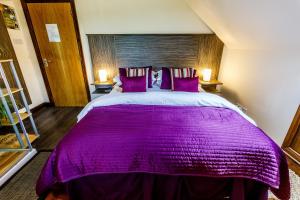 a bedroom with a large purple bed with two lamps at The Lodge on the Loch in Aboyne