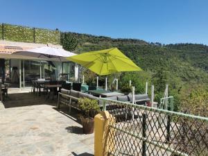 un patio con mesas y sillas y una sombrilla amarilla en Chambre d'hôtes casa di l'apa, en Venaco