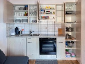a kitchen with white cabinets and a sink and an oven at Chalet Dennda Nr 27 in Rosswald