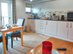 a kitchen with white cabinets and a table and a desk at Drysgol Lakeside - Bala Lake in Bala