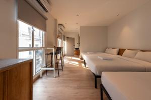 a hotel room with three beds and a bar at Boxpackers Pratunam in Bangkok