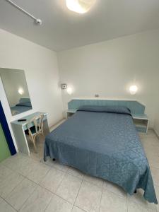 a bedroom with a blue bed and a table at Albergo Désirée in Alba Adriatica