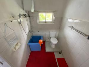 uma pequena casa de banho com WC e piso vermelho em Villa Berastagi Indah A17 - TEBU MANIS em Berastagi