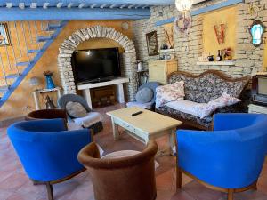 un soggiorno con divano, sedie e TV di Bastide Les Basses Royères a Robion en Luberon