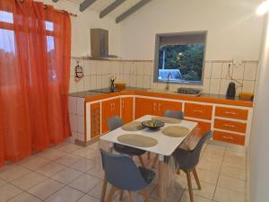 cocina con mesa y sillas y TV en La Familiale en Sainte-Rose