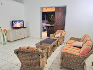 sala de estar con sillas de mimbre y TV en La Familiale en Sainte-Rose