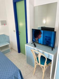 a room with a tv and a chair and a bed at Albergo Désirée in Alba Adriatica