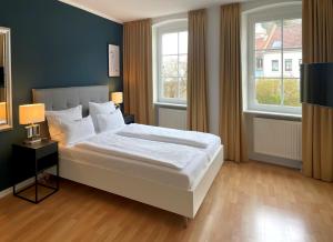 a bedroom with a large white bed with two windows at DK Hotel Deutscher Kaiser in Heidelberg