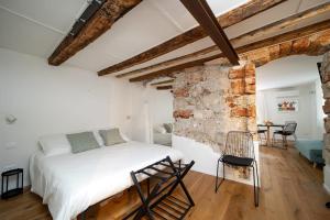 een slaapkamer met een wit bed en een stenen muur bij Casa Gagini in Palermo