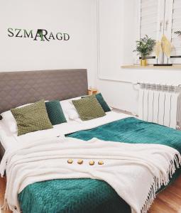 uma cama grande com lençóis e almofadas verdes e brancos em Szmaragd em Rabka