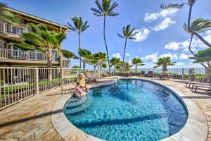 a swimming pool with palm trees and a building at Waipouli Beachfront Condo with Balcony and Ocean Views in Kapaa