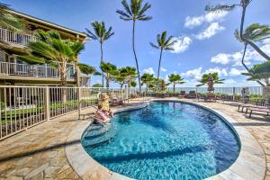 een zwembad met palmbomen en een gebouw bij Waipouli Beachfront Condo with Balcony and Ocean Views in Kapaa