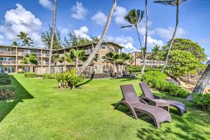 a yard with two chairs in front of a building at Waipouli Beachfront Condo with Balcony and Ocean Views in Kapaa