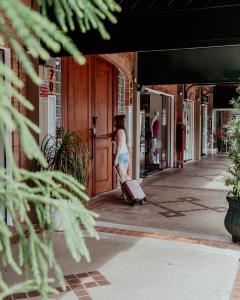 a woman walking down a sidewalk with a suitcase at Bloom Guesthouse in Holambra