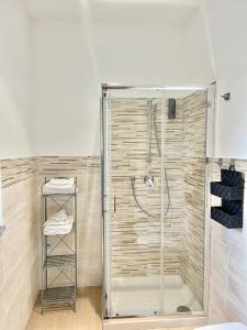La salle de bains est pourvue d'une douche avec une porte en verre. dans l'établissement Palazzo Proietti Bilo 2, à Biella