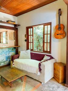 Mambembe Hostel - Ilha Grande في أبراو: غرفة نوم مع سرير وجيتار على الحائط