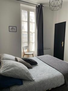 a bedroom with a bed and a chair and a window at Le charmant quai bourgeois in Bordeaux