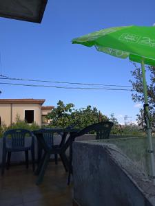 a table and chairs and an umbrella on a patio at Affittacamere Cooperativa Olistica in Mamoiada