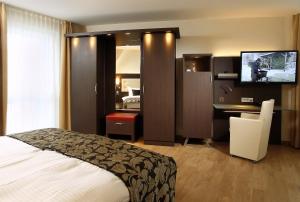 um quarto de hotel com uma cama, uma secretária e uma televisão em Hotel Simonshof em Wolfsburg