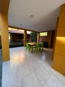 un patio con mesa de madera y sillas verdes en Casa de verano, en Santa Fe de Antioquia