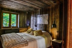 ein Schlafzimmer mit einem großen Bett an einer Holzwand in der Unterkunft Chalet de luxe sur les pistes - 5 chambres in Combloux