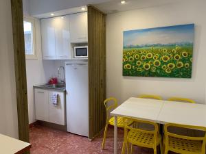 a kitchen with a table and yellow chairs and a painting at Doranda Rooms Las Canteras in Las Palmas de Gran Canaria