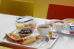 una bandeja de alimentos para el desayuno y café en una mesa en Premiere Classe Le Mans Ouest Universite en Le Mans