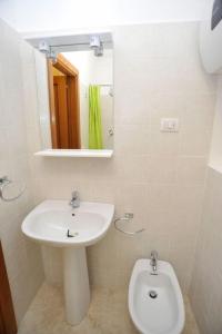 W łazience znajduje się umywalka, toaleta i lustro. w obiekcie San Francesco Lodge w mieście Mattinata