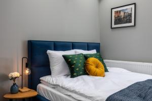1 cama con cabecero azul y almohadas verdes en Felicjanek 15, en Cracovia