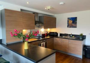 a kitchen with a vase of flowers on a counter at Contemporary, Cosy & Homely 2 Bed Apartment with High-Speed WIFI, Terrace & Free Parking overlooking Stourbridge Common Park & Coldham's Brook in Cambridge