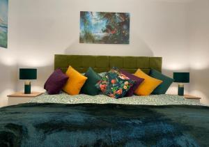 a bedroom with a bed with colorful pillows at Contemporary, Cosy & Homely 2 Bed Apartment with High-Speed WIFI, Terrace & Free Parking overlooking Stourbridge Common Park & Coldham's Brook in Cambridge
