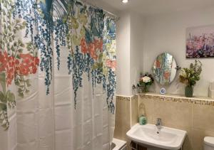 a bathroom with a shower curtain and a sink at Contemporary, Cosy & Homely 2 Bed Apartment with High-Speed WIFI, Terrace & Free Parking overlooking Stourbridge Common Park & Coldham's Brook in Cambridge