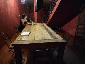 a woman sitting at a wooden table with a laptop at Casa Lopez in Chacras de Coria