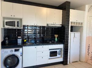 a kitchen with a washing machine and a microwave at Apartamento Encantador in Florianópolis