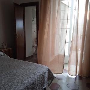 a bedroom with a bed and a window with curtains at Casa di Paola a Tufo in Santa Paolina