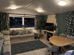 een woonkamer met een bank en een tafel bij Beautiful 3 bedroom caravan with hot tub - Tattershall Lakes in Tattershall