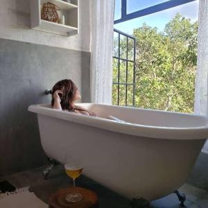 a woman sitting in a bath tub with a window at Segredo dos Pireneus in Pirenópolis