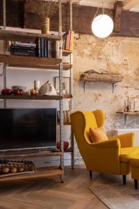 een woonkamer met een gele stoel en een televisie bij PASSAGE - historic boutique suite in Haarlem