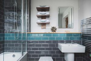 a blue tiled bathroom with a sink and a shower at Havener's in Fowey
