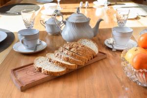 drewniany stół z chlebem, filiżankami do herbaty i pomarańczami w obiekcie Maison Sherman's house w mieście Scotstown