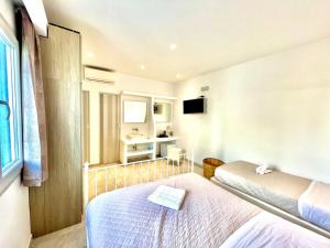 a hotel room with two beds and a window at La Villa Rooms in Mikonos