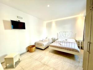 Habitación con 2 camas y TV en la pared. en La Villa Rooms en Mykonos ciudad