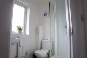 a bathroom with a toilet and a sink and a window at Comfortable 4 Bedroom Home in Milton Keynes by HP Accommodation with Free Parking, WiFi & Sky TV in Milton Keynes